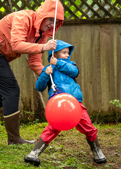 A child being helped onto an orange buoy swing.
